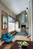 Bench with blue seat cushions against brick wall in front of modern fitted kitchen in open-plan interior