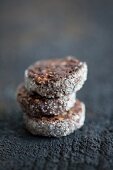 A stack of three chocolate and almond biscuits with a sugared rim