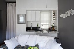 Sofa in front of white kitchen counter with space-saving pull-out tables