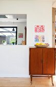 Simple wooden cabinet with castors against wall next to aperture in wall