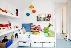 Weisses Bett mit Schubladen und Regal mit Spielsachen im Kinderzimmer