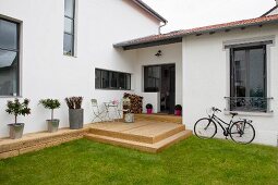 Modern house with rustic wooden terrace, lawn and bicycle