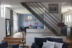 Elegant, open-plan living area with steel staircase and oak flooring in harmonious blend of grey and blue shades