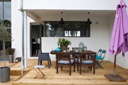 Überdachte Holzterrasse mit Outdoormöbeln und violettem Sonnenschirm