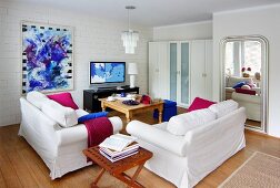 Living room furnished in white with bold accents of magenta and royal blue
