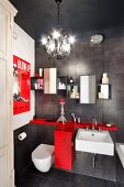 Vintage bathroom with charcoal tiles, red storage cabinet, film poster and chandelier