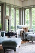 Pale grey armchair and footstool in corner in front of floor-to-ceiling lattice windows