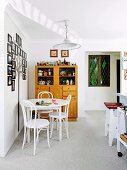 Retro Geschirrschrank mit Figurensammlung und weißer Bistrotisch mit Stühlen vor Wanddekoration mit gerahmten Familienfotos