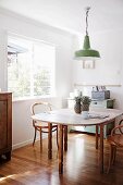 Extendible wooden dining table, wooden chairs, green retro pendant lamp, vintage cabinet and glossy parquet floor