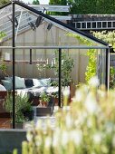View into cosily furnished greenhouse with scatter cushions on corner sofa