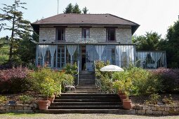 Treppenaufgang durch den Garten zu einem Haus mit Wintergarten