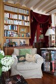 Bookcase, antique furniture, curtain on doorway and scatter cushions on armchair in classic living room