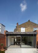 One-storey, modern extension in back yard of traditional, British brick house