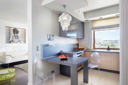 Victoria Ghost chairs at dining table in open-plan fitted kitchen; view into living area with black and white portrait