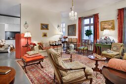 Mit antiken Sitzmöbeln und Beistelltischen gefüllter Wohnraum, Mustermix mit Orientteppich und traditionellen Polsterstoffen