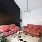 Sofa set with dusky pink brocade upholstery and delicate, curved metal coffee table on animal-skin rug in modern interior with black stucco lustro wall in background