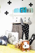 Soft toys, cushions with animal motifs, trousers hung from wall hooks and graphic pattern on wall