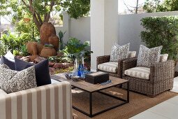 Outdoor seating area with coffee table, wicker armchairs, sofa and decorative terracotta pots in background
