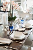 Detail of table set with crystal glasses, white crockery, silver cutlery and orchid