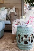 Ornate, drum-shaped ceramic table next to armchair