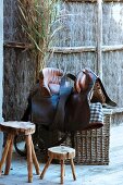 Rustic wooden stool next to saddle on top of basket outdoors