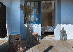 Rattan Hocker mit Sitzkissen und Pampasgras auf Holzterrasse mit Blick ins Schlafzimmer