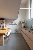 Elongated kitchen counter with pale wooden fronts in kitchen dining room with gallery