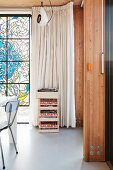 Stack of wooden crates in front of floor-length pale curtain next to stained glass window