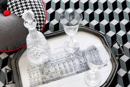Glasses and crystal carafe on tray on bedspread with op-art graphic pattern
