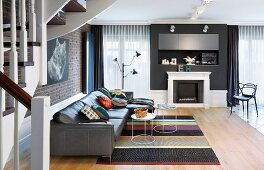 Open-plan interior with coffee tables, leather sofa, striped rug and traditional fireplace