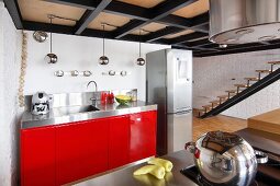 Kitchen counter with red base units next to stainless steel fridge-freezer in loft apartment
