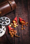 Three types of nuts in paper bags next to film-themed decorations