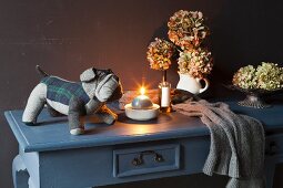 Candle, soft toy and hydrangeas on grey console table