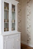 White vintage dresser and patterned wallpaper