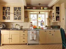 Kitchen counter with cream wooden fronts below window in rustic kitchen