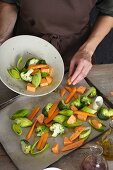 Sliced, marinated vegetables being arranged on a baking tray