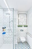 Modernes Bad in Weiß mit Wand- & Bodenfliesen, verglaster bodenebener Dusche und modernem Wandbild über Hängetoilette in Nische