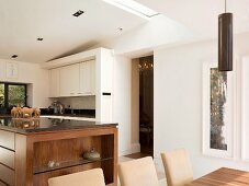 View across dining area into open-plan kitchen with solid wood counter and white wall units