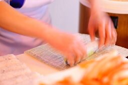 Sushi being made: rice being rolled in a bamboo mat