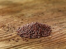 A pile of brown mustard seeds on a wooden surface
