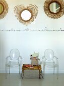 Wicker trunk between Ghost chairs below round mirrors with sunburst frames