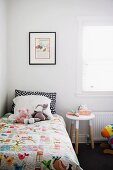 Soft toys and hand-made quilt on child's bed next to stool