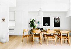 Large wooden table, Scandinavian wooden chairs and white walls in open-plan dining area