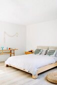 Pale wooden furniture and white wall in purist bedroom
