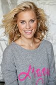 Blonde Frau in grauem Pulli mit pinkfarbener Schrift 'Magic'