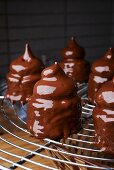 Meringues with chocolate glaze on a wire rack