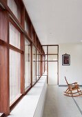 Purist interior of modern, Indian house with stone floor and continuous strip of wood-framed windows