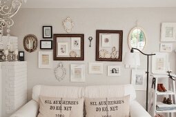 White sofa with hessian scatter cushions below pictures and picture frames on wall
