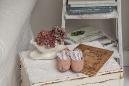 Dried hydrangeas in white china pot and pink ballet shoes on lace doily