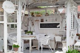 Shabby Gartenpavillon mit hellen Möbeln und Flohmarktartikeln